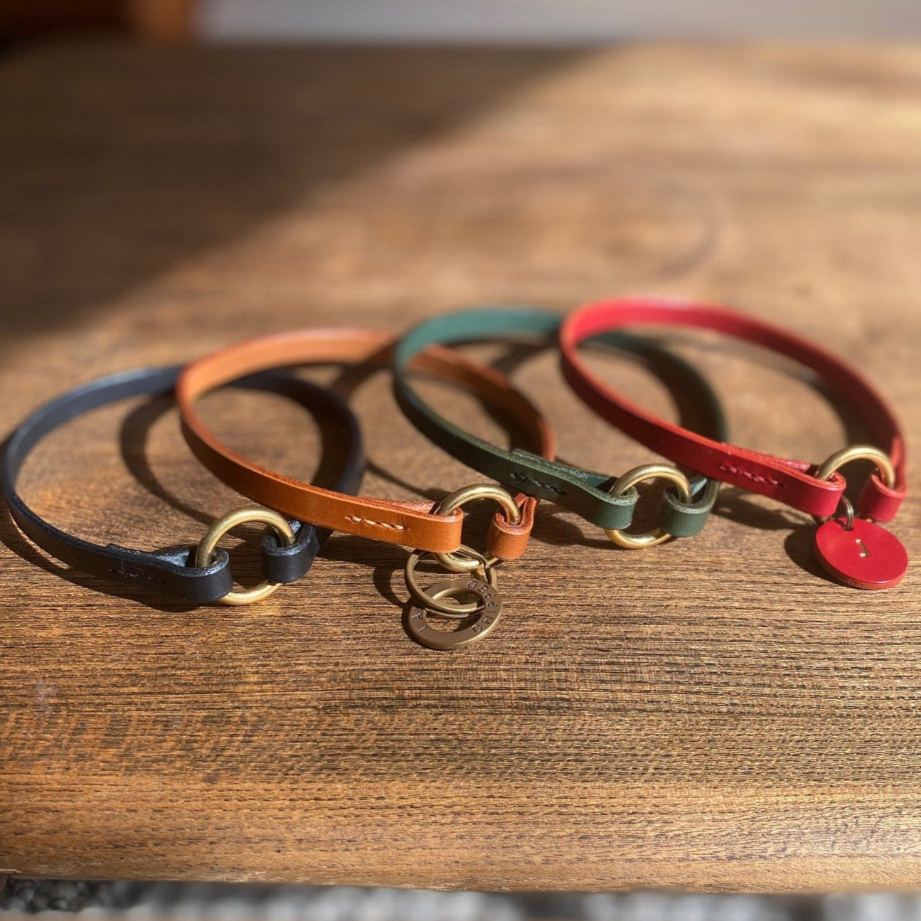 Four colorful leather dog collars on a wooden surface