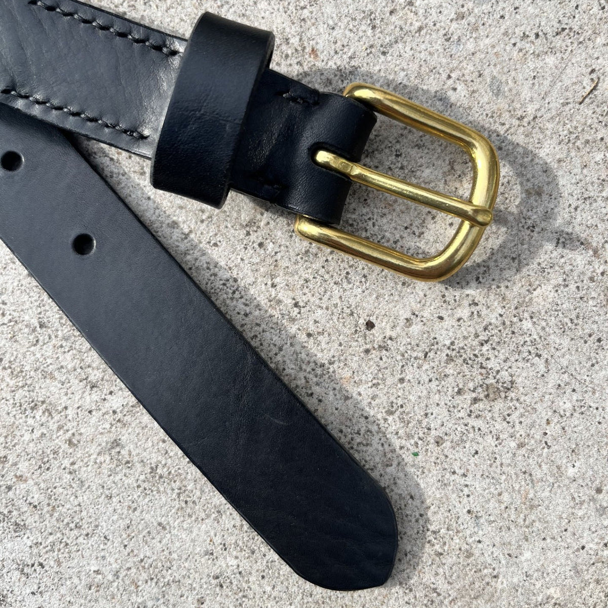 Black belt with a brass buckle on a stone background
