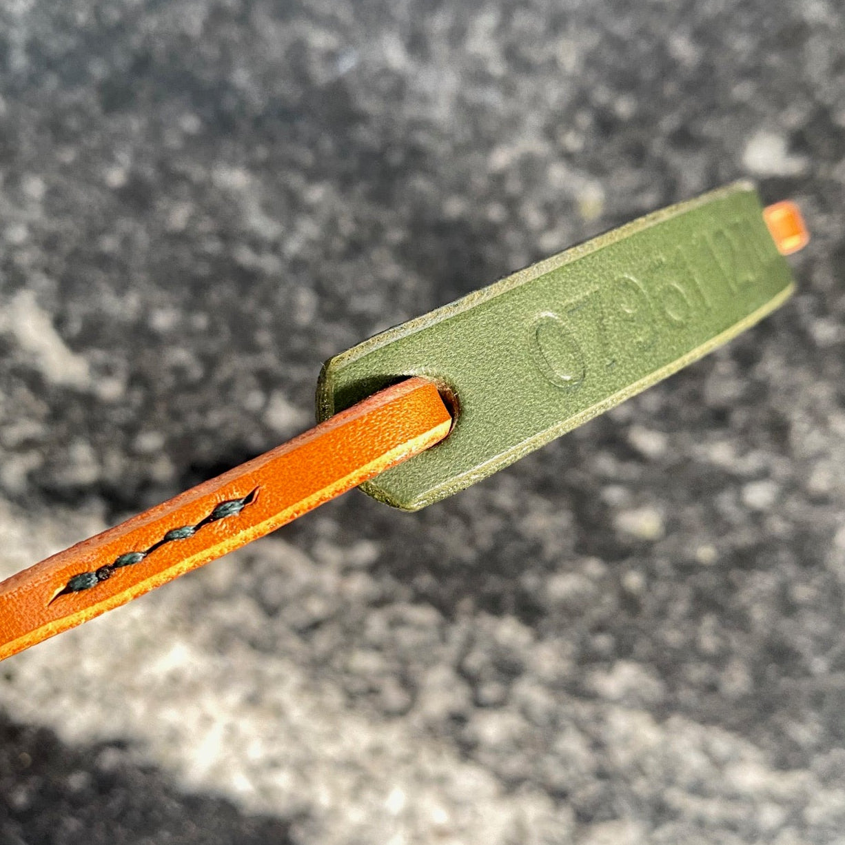 Close-up of a green and tan ID collar on a granite surface