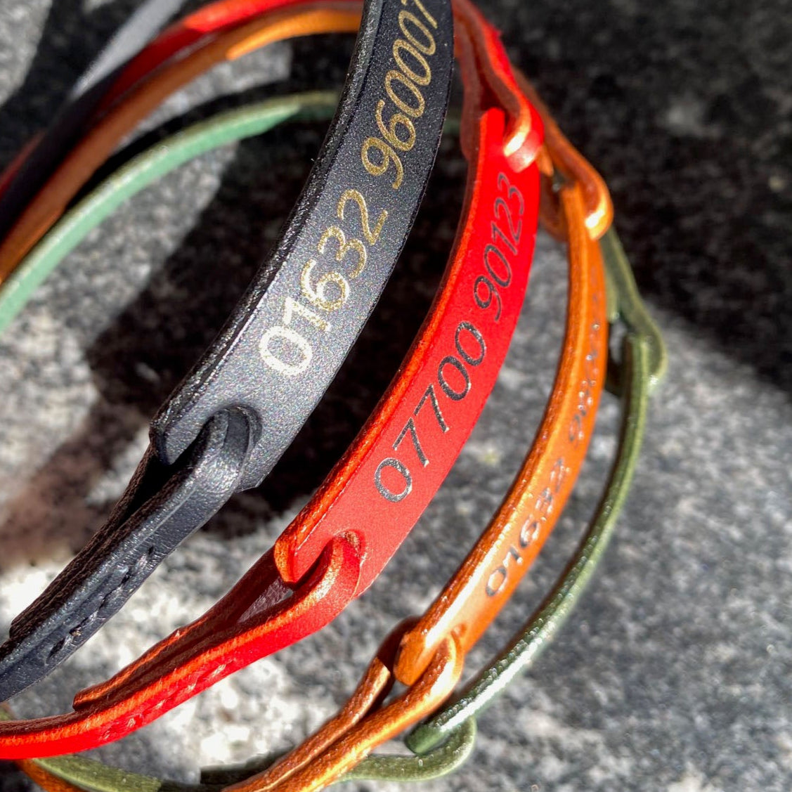Colourful leather ID collars  on a granite surface